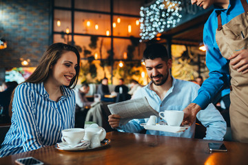 friends having cup of tea in cafeteria, waiter serving