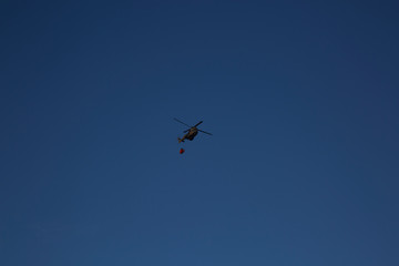 Helicopter / chopper flies to drop water on wildfire