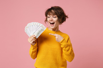 Excited young brunette woman in yellow sweater posing isolated on pastel pink background. People...