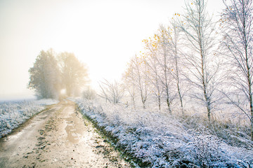 A beautiful scenery of a gravel road in the late autumn with first snow. Northern Europe landscape at the beginning of winter.
