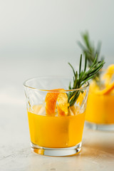 Honey bourbon cocktail with rosemary simple syrup or homemade whiskey sour cocktail drink with orange and rosemary. Decorate orange peel. Light concrete surface.