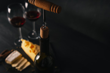 cheese and wine on the table. two glasses of red wine next to cheese. black wooden table. place for...