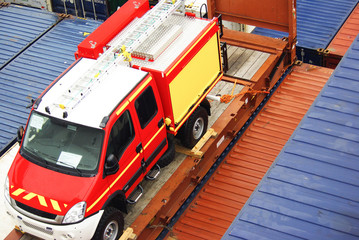 Fire fighting truck secured on flatrack container and loaded on board of container ship for delivery by sea