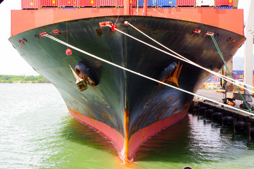 Photo of the bow front part of the moored container ship, with mooring lines and anchors.