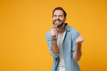 Joyful young man in casual blue shirt posing isolated on yellow orange background. People lifestyle...