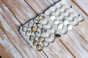 Fresh and boiled quail eggs on craft cell on wooden background