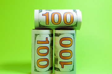 Hundred dollar banknotes twisted into a tube on a green background, with copy space. Finance concept