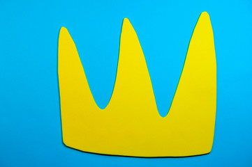 Yellow paper crown on a blue background. Colour contrast