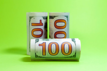 Three hundred dollar banknotes rolled into a tube on a green background, with copy space. Finance concept