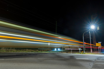 Fototapeta na wymiar Doppeldecker Reisezug befährt einen Überweg bei Nacht