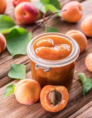 Apricot jam and ripe apricots on the table.