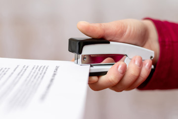 Girl stapler fastens sheets of paper (documents) in the office_