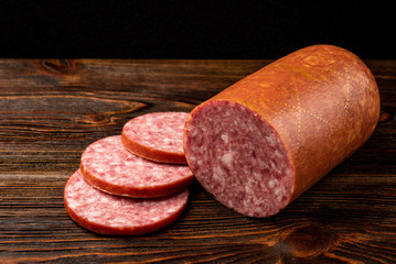 Smoked sausage on dark wooden background.