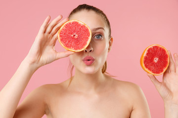 Close up blonde half naked woman 20s perfect skin nude make up blue eyes hold in hand grapefruit isolated on pastel pink background studio portrait. Skin care healthcare cosmetic procedures concept.