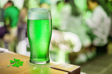 Glass of green beer stands on a table in a pub during the celebration of St. Patrick's Day.