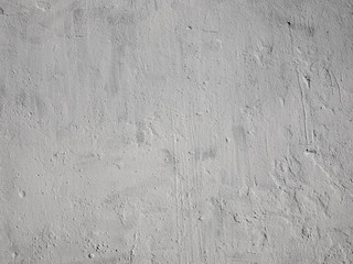 Texture of light gray old stucco on a concrete wall. Old unevenly painted concrete wall.