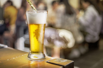 Glass of beer stands on a table in a pub.