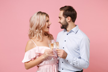 Joyful young couple two guy girl in party outfit celebrating posing isolated on pastel pink background. People lifestyle Valentine's Day Women's Day birthday holiday concept. Hold glass of champagne.