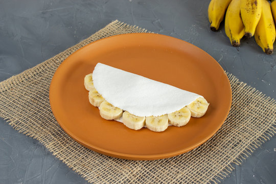 Tapioca filled of banana slices and condensed milk. Pieces of cassava and banana on the back. (mandioca, yuca, mandioca, araruta brasileira)