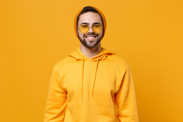 Obraz premium Smiling young hipster guy in fashion casual clothes posing isolated on yellow orange wall background studio portrait. People sincere emotions lifestyle concept. Mock up copy space. Looking camera.