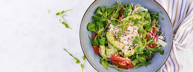 Fresh salad with chicken breast, corn salad, cucumber, avocado and tomato. Chicken salad. Italian cuisine. Healthy food concept. Top view, overhead, banner