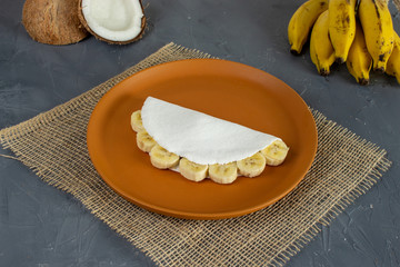 Tapioca filled of banana slices and condensed milk. Pieces of cassava and banana on the back. (mandioca, yuca, mandioca, araruta brasileira)