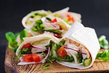 Fresh tortilla wraps with chicken and fresh vegetables on wooden board. Chicken burrito. Mexican food. Healthy food concept. Mexican cuisine.