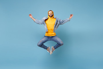 Relaxed young hipster guy in fashion jeans denim clothes posing isolated on pastel blue background. People lifestyle concept. Mock up copy space. Jump hold hands in yoga gesture, relaxing meditating.