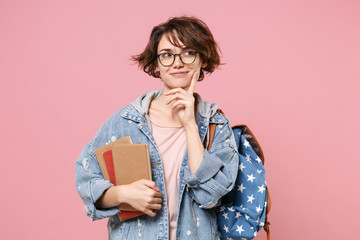 Pensive girl student in denim clothes glasses backpack isolated on pastel pink background....