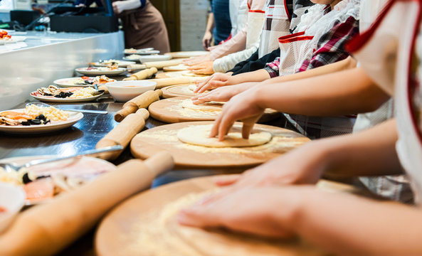 Children cook pizza. Master class from the chef in a restaurant, Close-up of children's hands roll out the dough