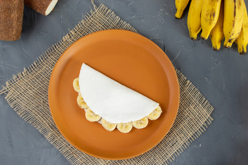 Banana Tapioca, a tradicional Brazilian food. Made from starch of cassava. With banana e casavas in the back.  Close up