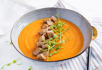 Pumpkin soup in a bowl served with croutons and pea sprouts. Vegan diet soup. Vegetarian food.