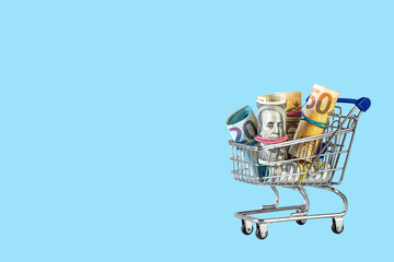 Shopping cart full of money isolated on blue background