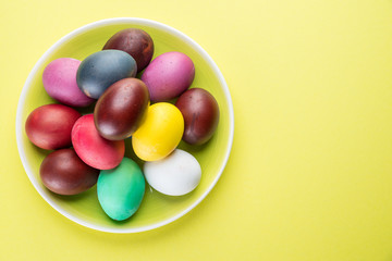 Colorful Easter eggs as an attribute of Easter celebration on the yellow plate.