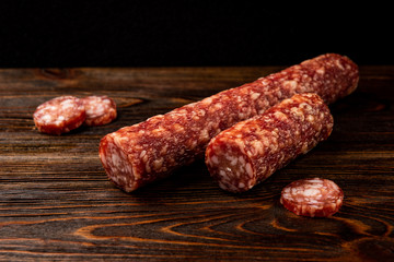 Smoked sausage on dark wooden background.