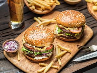 Hamburgers and French fries on the wooden tray.