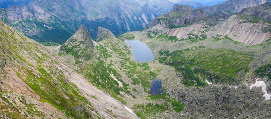 View of the mountain valley from the pass. Beautiful rocks and lake. Travel in the mountains. Sayan Mountains in Siberia, Ergaki.