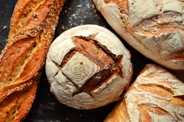 Bakery products. Crispy, beautiful bread on a dark background. Buckwheat, without yeast, wheat bread with flax and sunflower seeds. Top view, place for text.