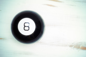 Magic ball of predictions figure eight on a light wooden background.