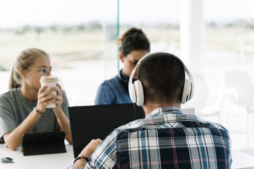 Man with white helmets sitting next to two girls at the same table meeting