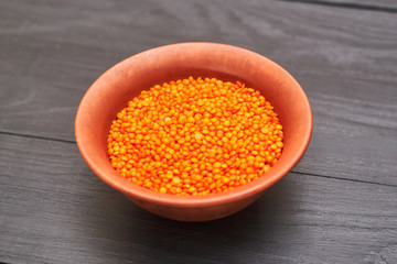lentil grains in a plate on a black wooden background.
