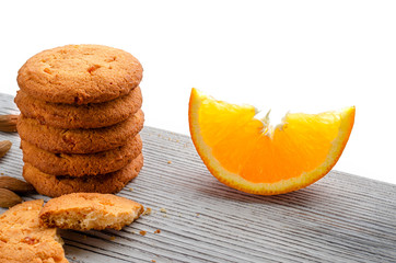Round, orange biscuits with colorful candied fruits and a slice of juicy orange lying on a wooden table