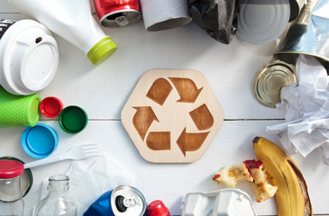 A lot of different garbage on the table and the recycling icon between them