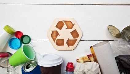 A lot of different garbage on the table and the recycling icon between them