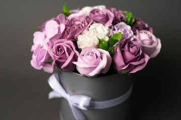 Flowers in bloom: Bouquet of lilac and white roses in a gray round box on a gray background.