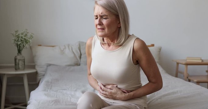 Sick mature woman hold belly feel abdominal ache in bed