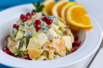 Diet fruit salad for breakfast. Kiwi orange banana and apple diced and seasoned with yogurt with honey. Healthy food, vegetarianism.