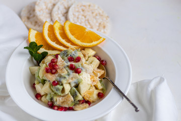 Diet fruit salad for breakfast. Kiwi orange banana and apple diced and seasoned with yogurt with honey. Healthy food, vegetarianism.