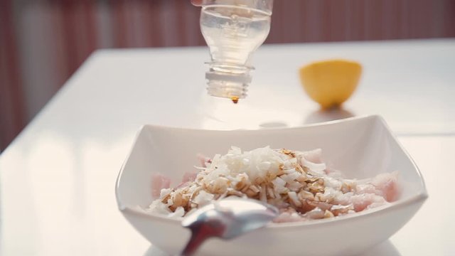 Female hand pouring soy sauce from bottle on sliced chopped raw fresh chicken and onion pieces in plate. concept add, mixing, cut. asian meal. housewife homemade cooking on kichen.