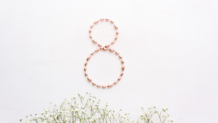 monochrome composition with white flowers and necklace in the shape of the number 8.Valentines Day, Birthday, Happy Women's Day, Mother's day. Flat lay. copy space